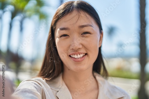 Chinese woman smiling confident making selfie by camera at street
