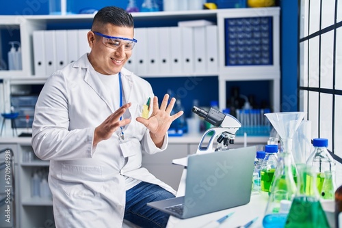 Young latin man scientist smiling confident having video call at laboratory