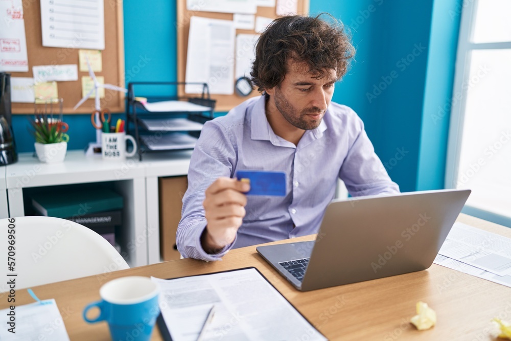 Young hispanic man business worker using laptop and credit card at office