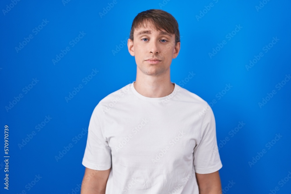 Caucasian blond man standing over blue background looking sleepy and tired, exhausted for fatigue and hangover, lazy eyes in the morning. Caucasian blond man standing over blue background looking sleepy and tired, exhausted for fatigue and hangover, lazy eyes in the morning.
