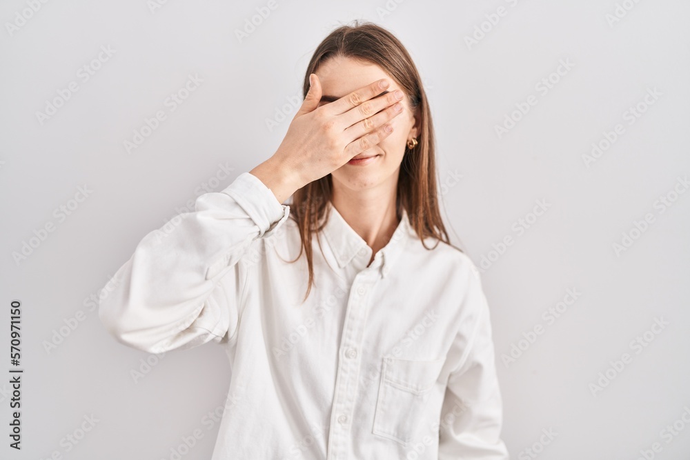 Young caucasian woman standing over isolated background covering eyes with hand, looking serious and sad. sightless, hiding and rejection concept Young caucasian woman standing over isolated background covering eyes with hand, looking serious and sad. sightless, hiding and rejection concept