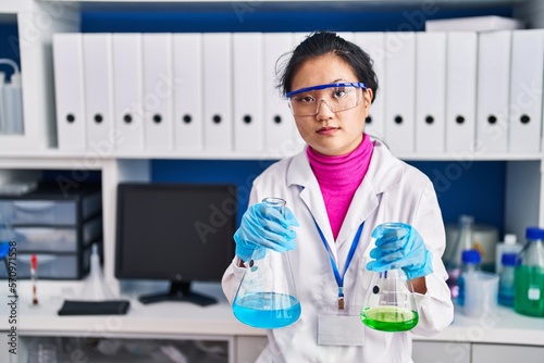 Young asian woman working at scientist laboratory skeptic and nervous  frowning upset because of problem. negative person.