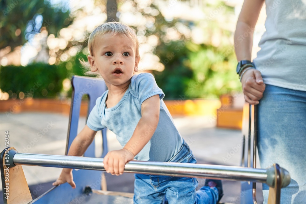 Mother and son playing on swing at park playground Mother and son playing on swing at park playground