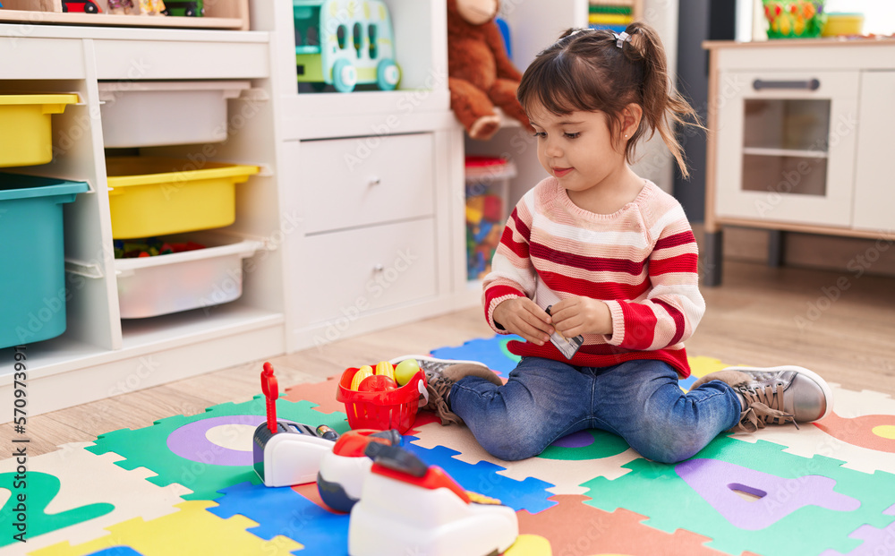 Adorable hispanic girl playing supermarket game sitting on floor at kindergarten Adorable hispanic girl playing supermarket game sitting on floor at kindergarten