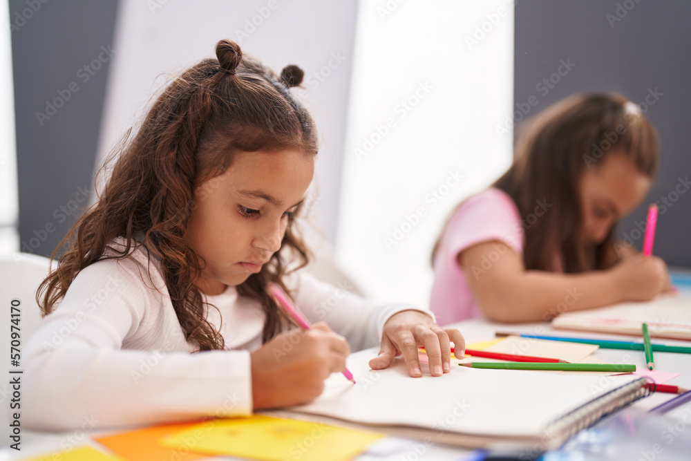 Two kids preschool students sitting on table drawing on paper at classroom Two kids preschool students sitting on table drawing on paper at classroom