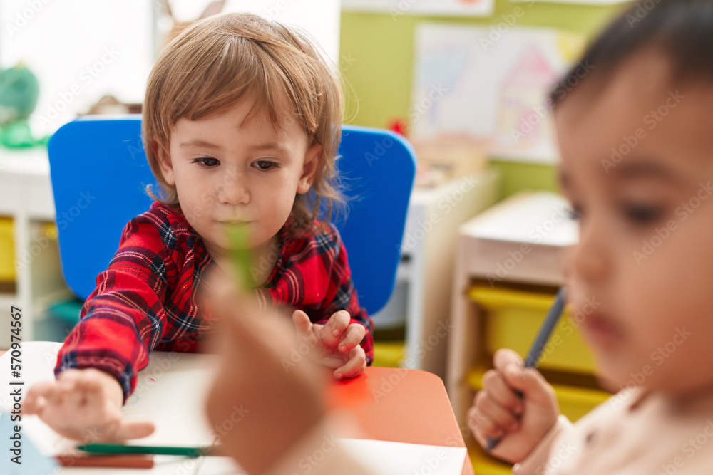 Two kids preschool students sitting on table drawing on paper at kindergarten Two kids preschool students sitting on table drawing on paper at kindergarten