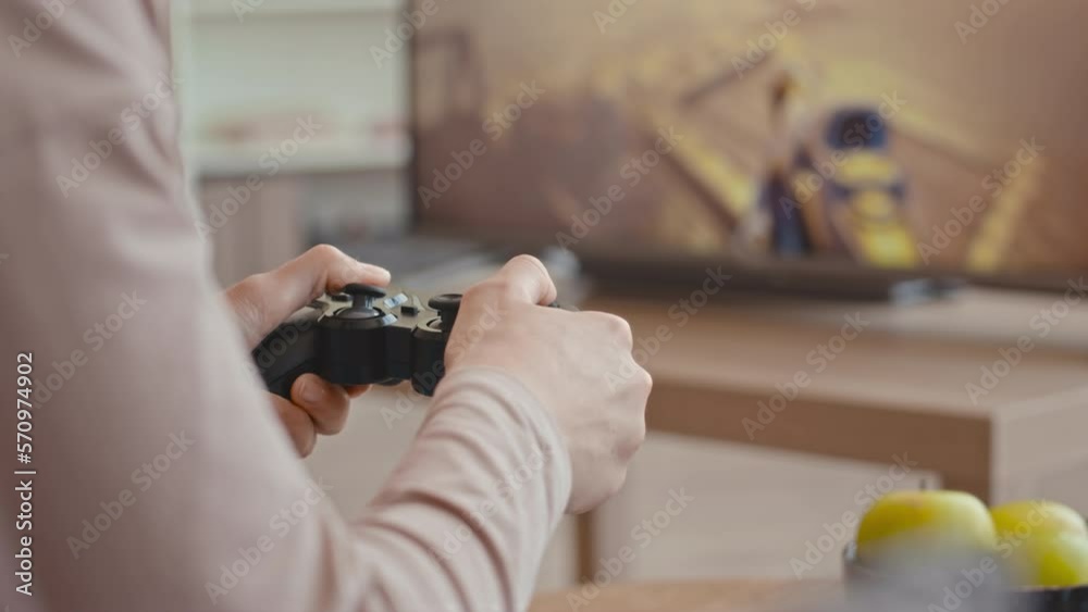 Unrecognizable female gamer using controller while playing fps game on console at home on weekend Unrecognizable female gamer using controller while playing fps game on console at home on weekend