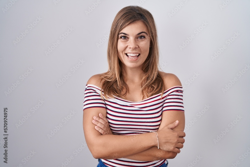 Young hispanic woman standing over isolated background happy face smiling with crossed arms looking at the camera. positive person. Young hispanic woman standing over isolated background happy face smiling with crossed arms looking at the camera. positive person.
