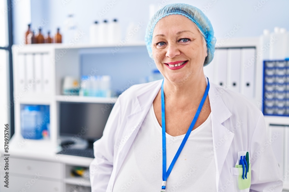 Middle age blonde woman wearing scientist uniform standing at laboratory