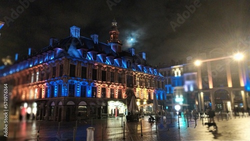 Lune voilée dans le ciel de Lille au-dessus de la vieille bourse éclairée de bleue effets estompés