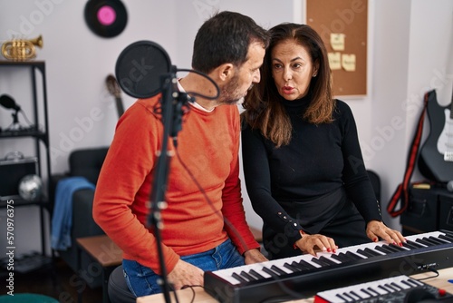 Middle age man and woman musicians having keyboard piano class at music studio © Krakenimages.com