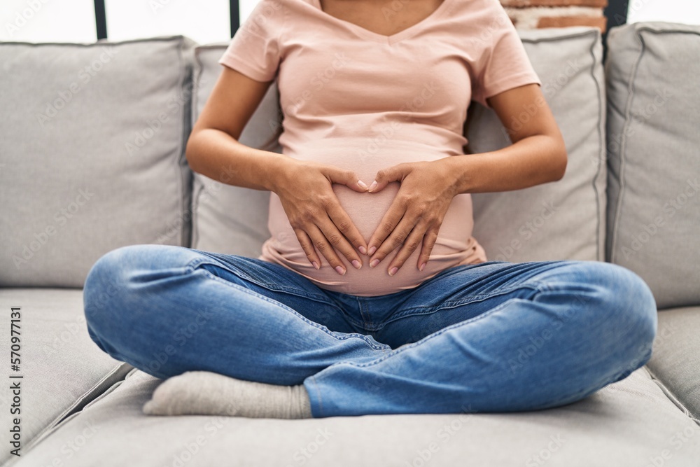 Young latin woman pregnant touching belly sitting on sofa at home Young latin woman pregnant touching belly sitting on sofa at home