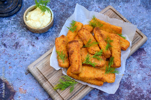Close up of   Crispy breaded  deep fried fish fingers with breadcrumbs served  with remoulade sauce and  lemon Cod Fish Nuggets on rustic wood table background