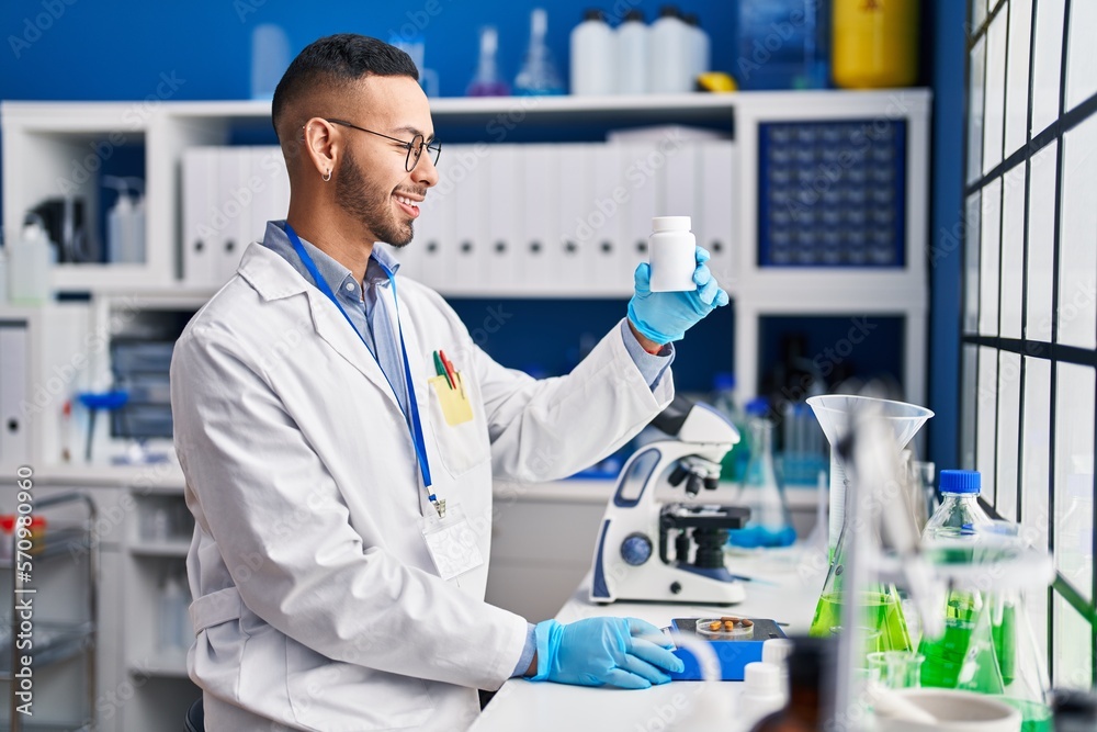 African american man scientist smiling confident weighing pills at laboratory African american man scientist smiling confident weighing pills at laboratory