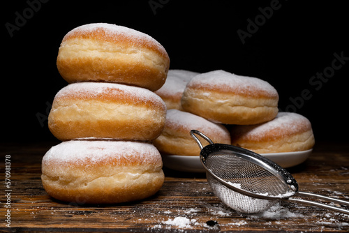 Polish pączki deep-fried doughnuts. Celebrating Fat Thursday (Tłusty czwartek) feast, traditional day in Poland. Pączek food, powdered sugar topped and filled with rose hip jam.