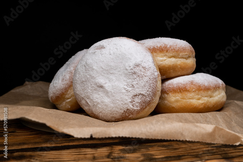 Polish pączki deep-fried doughnuts. Celebrating Fat Thursday, Tłusty czwartek feast, traditional day in Poland. Pączek food, powdered sugar topped and filled with rose hip jam.