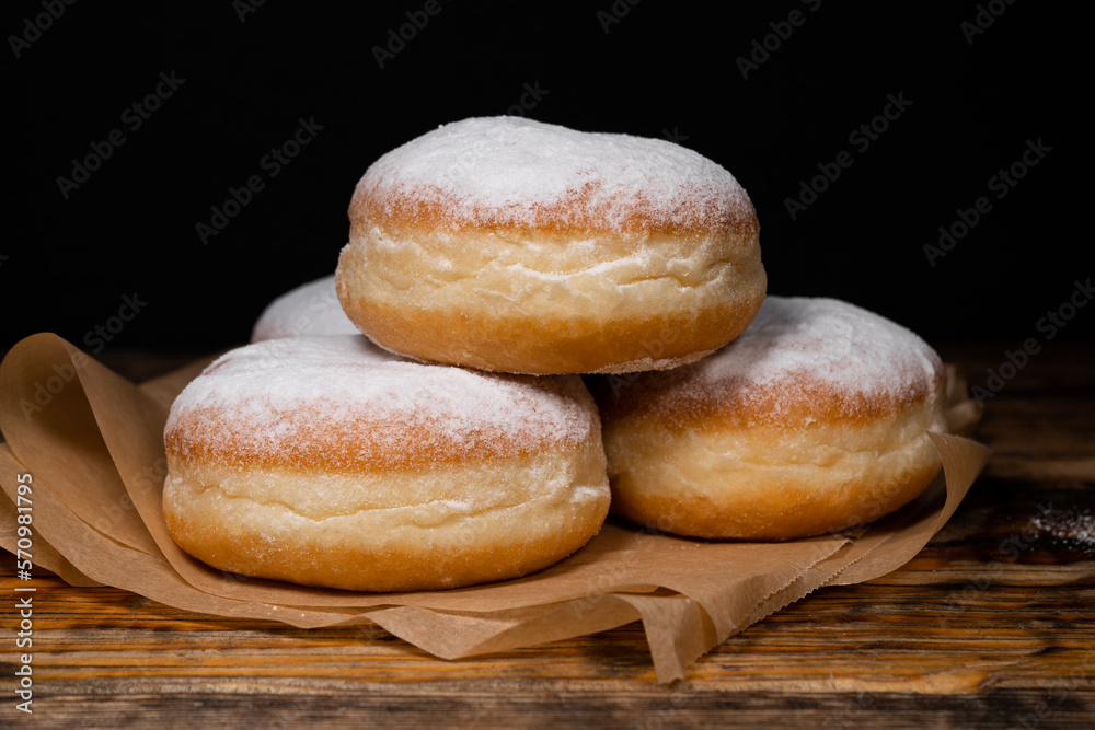 Polish pączki deep-fried doughnuts. Celebrating Fat Thursday (Tłusty czwartek) feast, traditional day in Poland. Pączek food, powdered sugar topped and filled with rose hip jam. Polish pączki deep-fried doughnuts. Celebrating Fat Thursday (Tłusty czwartek) feast, traditional day in Poland. Pączek food, powdered sugar topped and filled with rose hip jam.