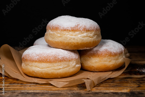 Polish pączki deep-fried doughnuts. Celebrating Fat Thursday (Tłusty czwartek) feast, traditional day in Poland. Pączek food, powdered sugar topped and filled with rose hip jam.