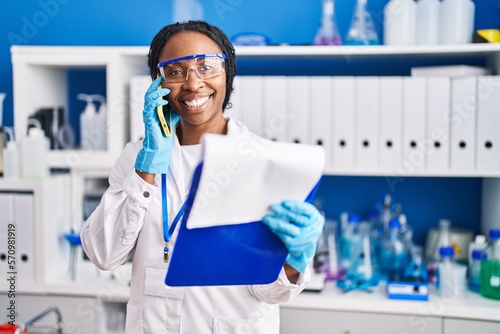 African american woman wearing scientist uniform talking on the smartphone laboratory
