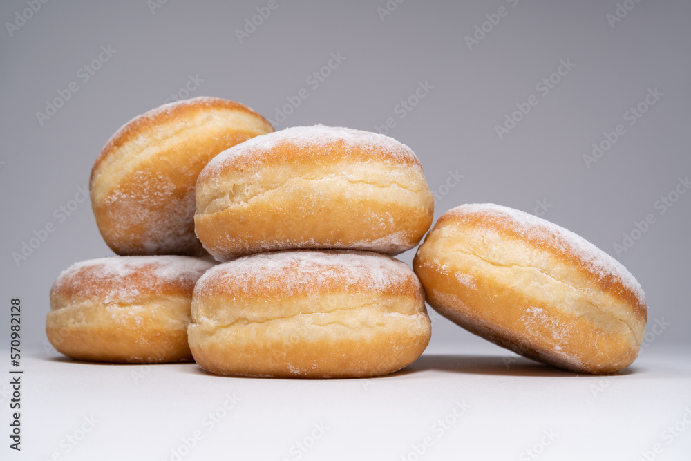 Polish pączki deep-fried doughnuts. Celebrating Fat Thursday, Tłusty czwartek feast, traditional day in Poland. Pączek food, powdered sugar topped and filled with rose hip jam. Polish pączki deep-fried doughnuts. Celebrating Fat Thursday, Tłusty czwartek feast, traditional day in Poland. Pączek food, powdered sugar topped and filled with rose hip jam.