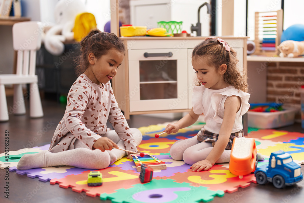 Fototapeta premium Two kids playing xylophone sitting on floor at kindergarten