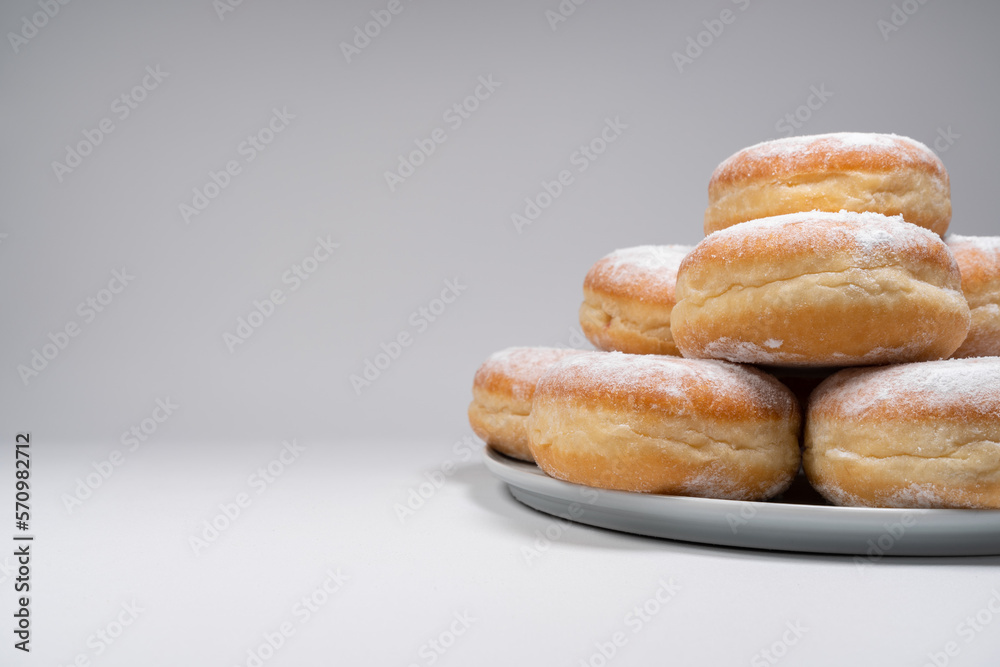 Polish pączki deep-fried doughnuts with copy space. Celebrating Fat Thursday (Tłusty czwartek) feast, traditional day in Poland. Pączek food, powdered sugar topped and filled with rose hip jam. Polish pączki deep-fried doughnuts with copy space. Celebrating Fat Thursday (Tłusty czwartek) feast, traditional day in Poland. Pączek food, powdered sugar topped and filled with rose hip jam.