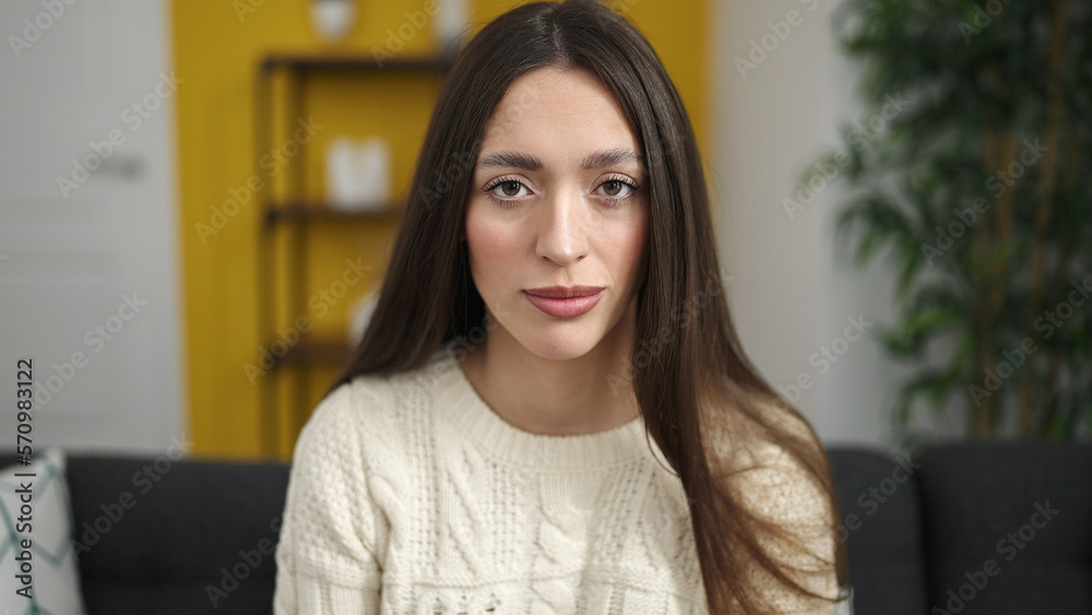Young beautiful hispanic woman sitting on sofa with relaxed expression at home Young beautiful hispanic woman sitting on sofa with relaxed expression at home