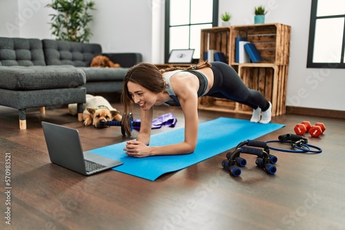 Young hispanic woman smiling confident having online abs exercise class at home