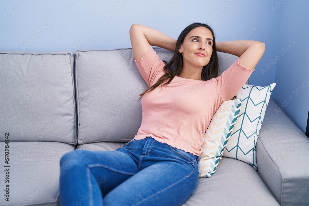Young beautiful hispanic woman relaxed with hands on head sitting on sofa at home Young beautiful hispanic woman relaxed with hands on head sitting on sofa at home