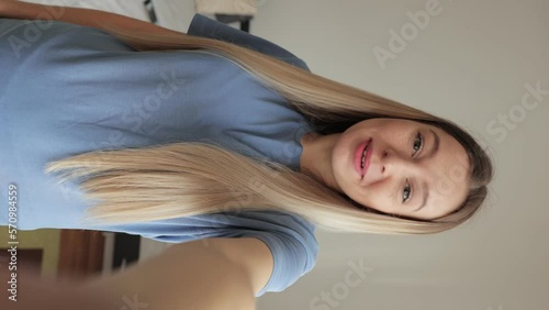 Vertical POV portrait of cheerful young woman talking via video chat using mobile phone looking at camera, on white isolated background in studio. Point of view of happy lady talking to camera.