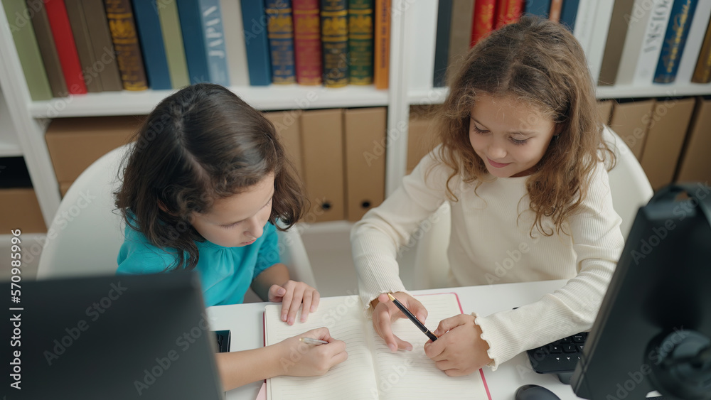 Two kids students using computer writing on notebook at classroom Two kids students using computer writing on notebook at classroom