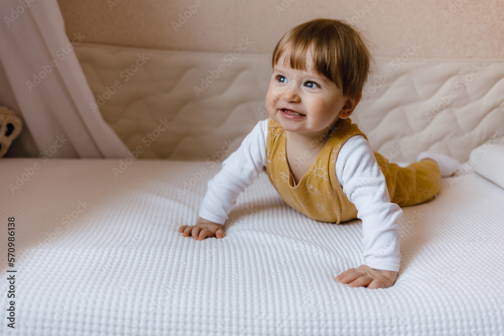 Naklejka premium Cute baby boy lying on white sheet at home, boy sitting on the bed.