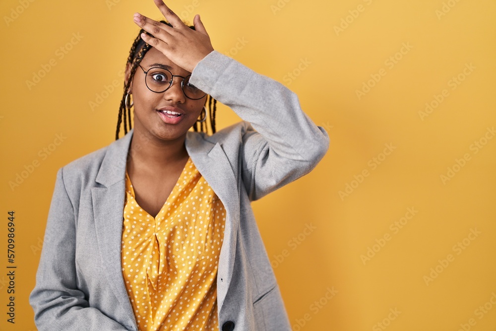 African american woman with braids standing over yellow background surprised with hand on head for mistake, remember error. forgot, bad memory concept. African american woman with braids standing over yellow background surprised with hand on head for mistake, remember error. forgot, bad memory concept.