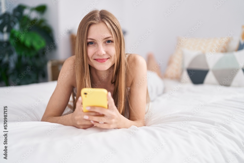 Young caucasian woman using smartphone lying on bed at bedroom Young caucasian woman using smartphone lying on bed at bedroom