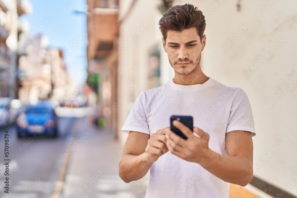 Young hispanic man using smartphone with serious expression at park Young hispanic man using smartphone with serious expression at park