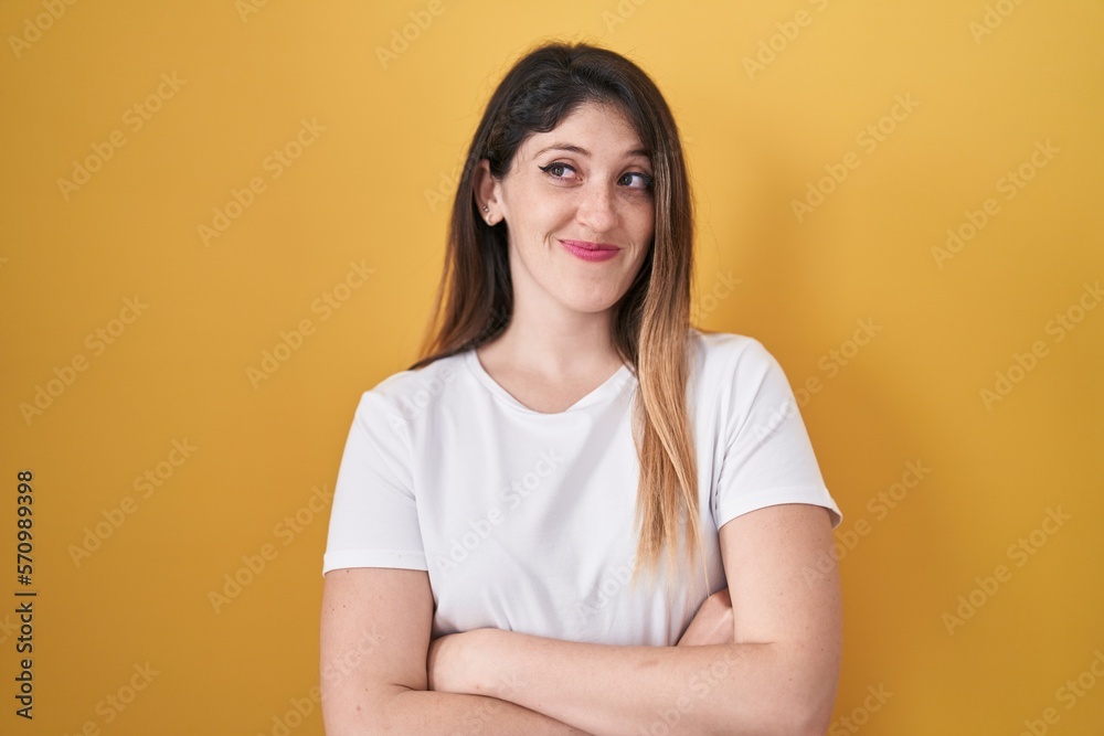 Young brunette woman standing over yellow background smiling looking to the side and staring away thinking. Young brunette woman standing over yellow background smiling looking to the side and staring away thinking.