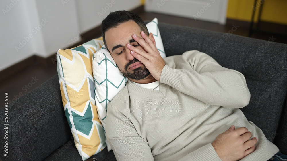 Obraz premium Young hispanic man lying on sofa with worry expression at home