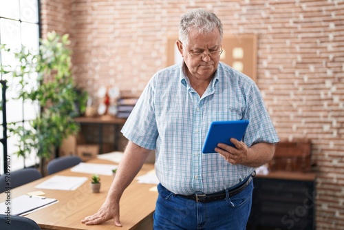 Middle age grey-haired man business worker using touchpad at office