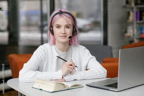Portrait of young beautiful woman, business woman smiling and looking at camera, receptionist using headset for video call. Young woman employee customer support services in headset