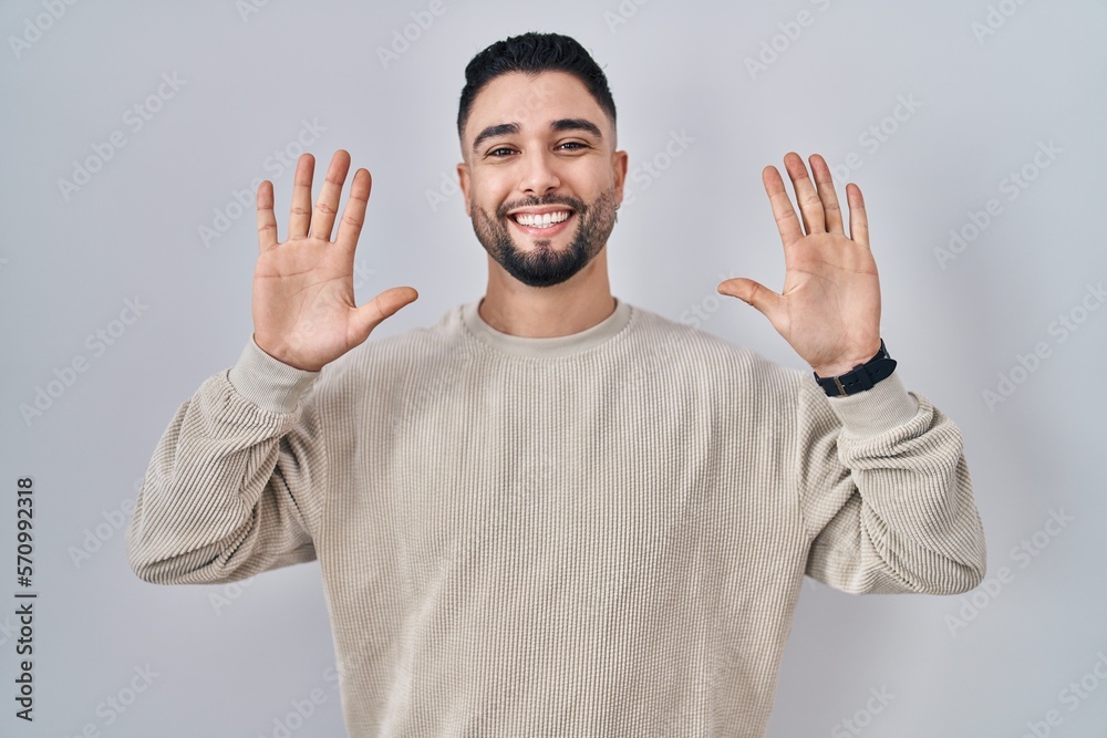 Young handsome man standing over isolated background showing and pointing up with fingers number ten while smiling confident and happy. Young handsome man standing over isolated background showing and pointing up with fingers number ten while smiling confident and happy.