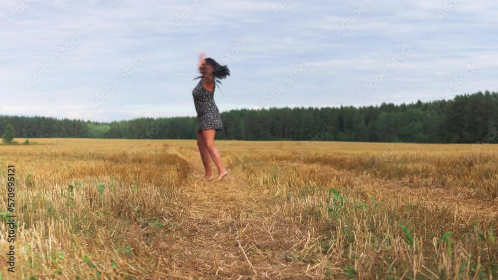 Young woman standing on a wheat field with sunrise on the background Young woman standing on a wheat field with sunrise on the background