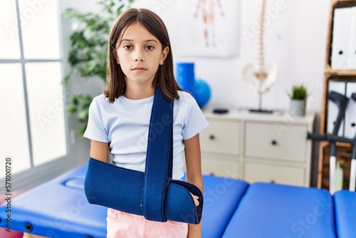 Young hispanic girl wearing arm on sling at rehabilitation clinic thinking attitude and sober expression looking self confident Free Download Young hispanic girl wearing arm on sling at rehabilitation clinic thinking attitude and sober expression looking self confident - GFXLoad