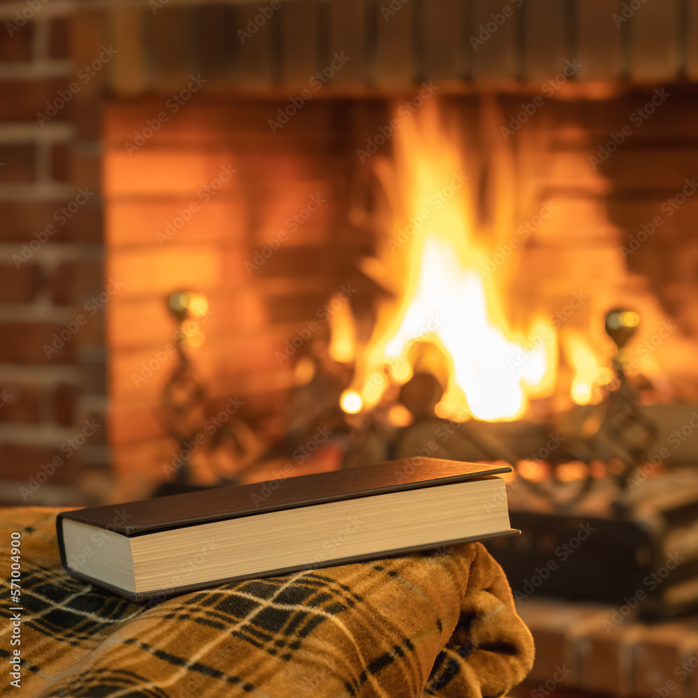 Books on top of a blanket in front of the cozy fire of the fireplace in