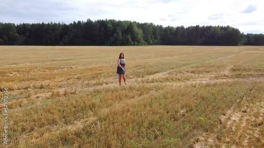 Aerial Drone Young woman standing and dance on a wheat field with sunrise on the background Aerial Drone Young woman standing and dance on a wheat field with sunrise on the background