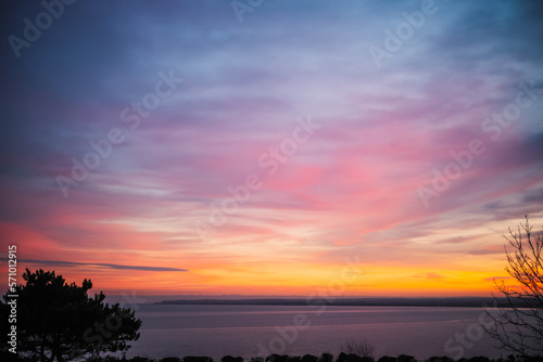 Beautiful blue and pink sky with a golden band at dusk over a bay of water.