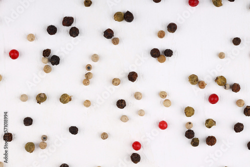 Red and black peppercorns are scattered on a white concrete, stone or slate background. view from above. close-up photo. pepper mixture