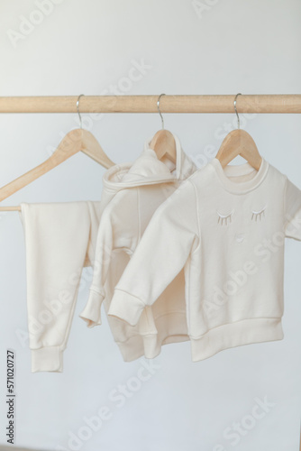 Wooden hanger for clothes with children's autumn outfit. joggers and a sweatshirt in wardrobe. Aesthetic minimalist baby fashion