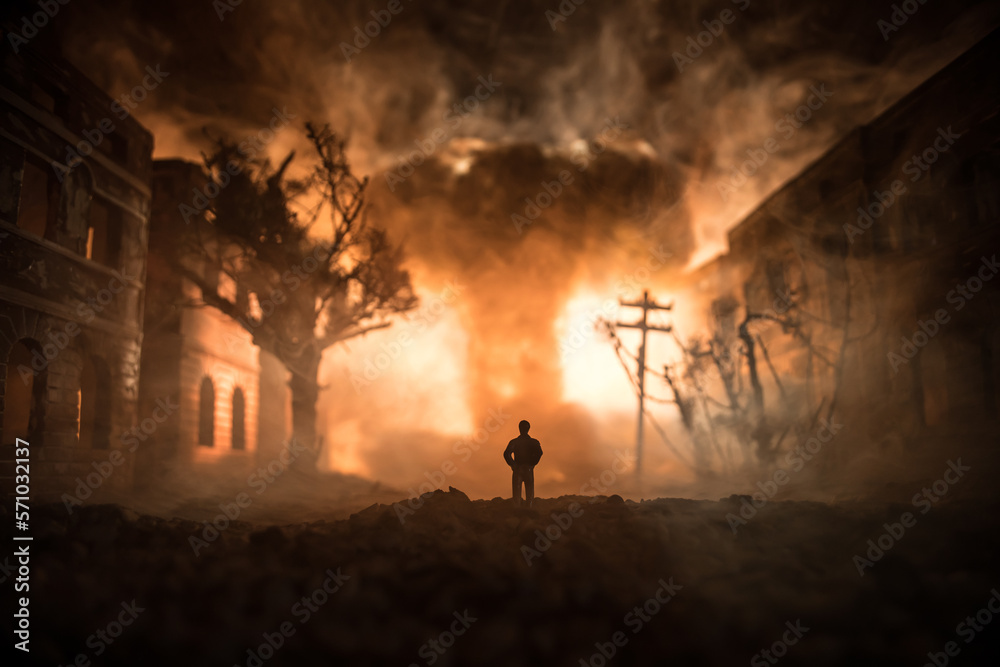 Artwork decoration. A man standing on a road of burnt up city. Apocalyptic view of city downtown as disaster film poster concept. Night scene. City destroyed by war.