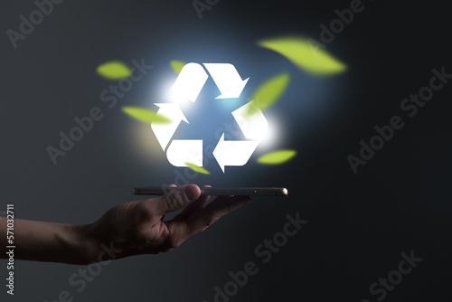 Hand holding recycle symbol on a screen of mobile phone. Mobile applications as asource of information about recycle and sustainability. photo
