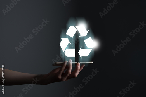 Hand holding recycle symbol on a screen of mobile phone. Mobile applications as asource of information about recycle and sustainability. photo